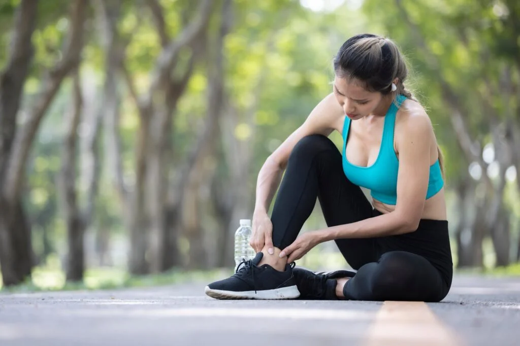 Active woman holding ankle in pain