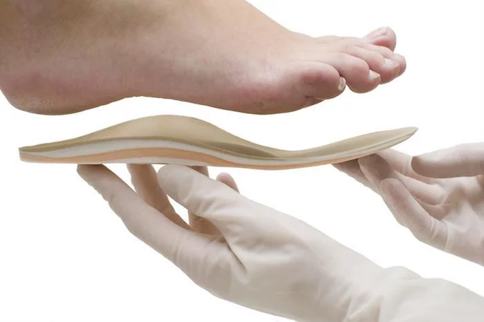 Provider holding custom orthotic insole near foot