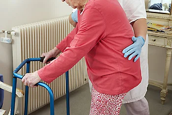 Provider assisting elderly patient using walker