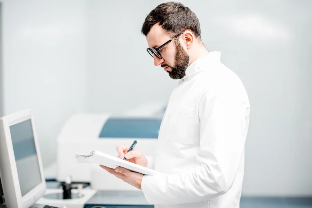 Doctor in lab coat writing clinical notes