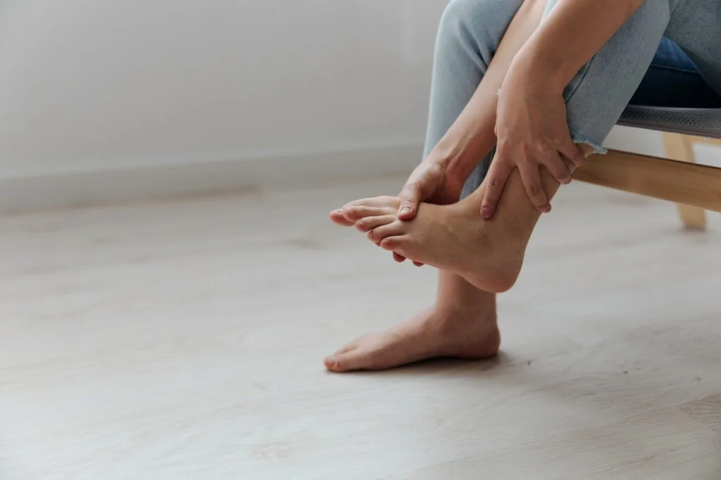 Person touching their bare foot and toes while seated