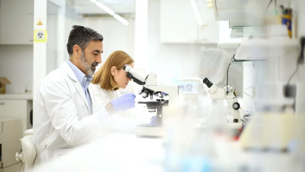 Lab technicians analyzing samples under microscopes