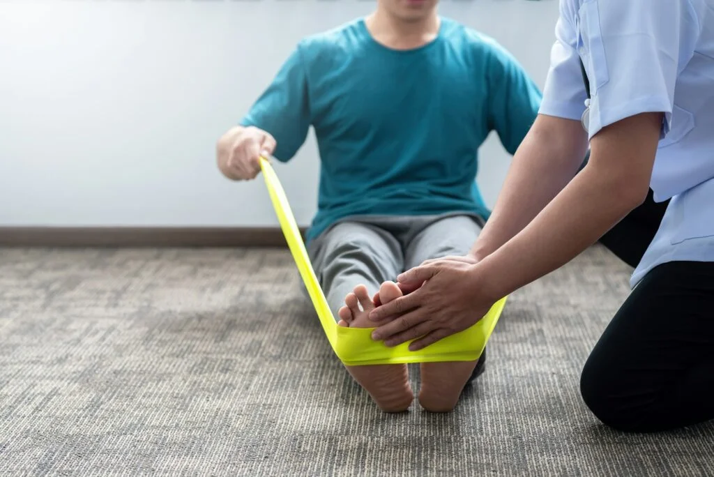 Therapist guiding patient's resistance band foot exercise