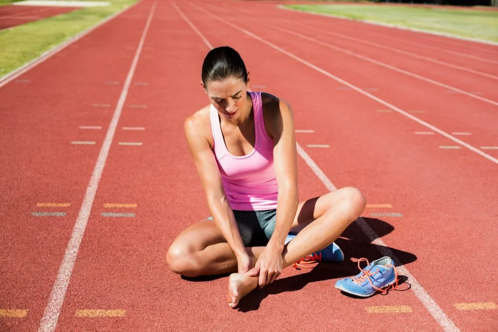 Runner holding forefoot in pain on track