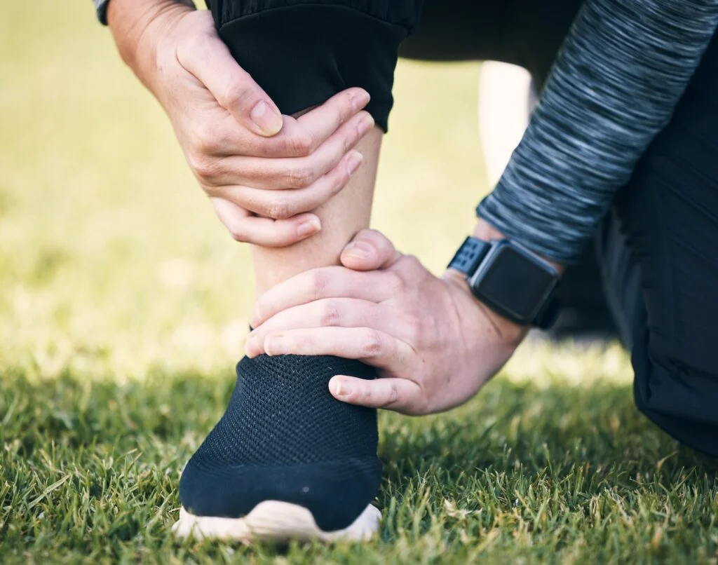 Athlete on grass holding injured ankle