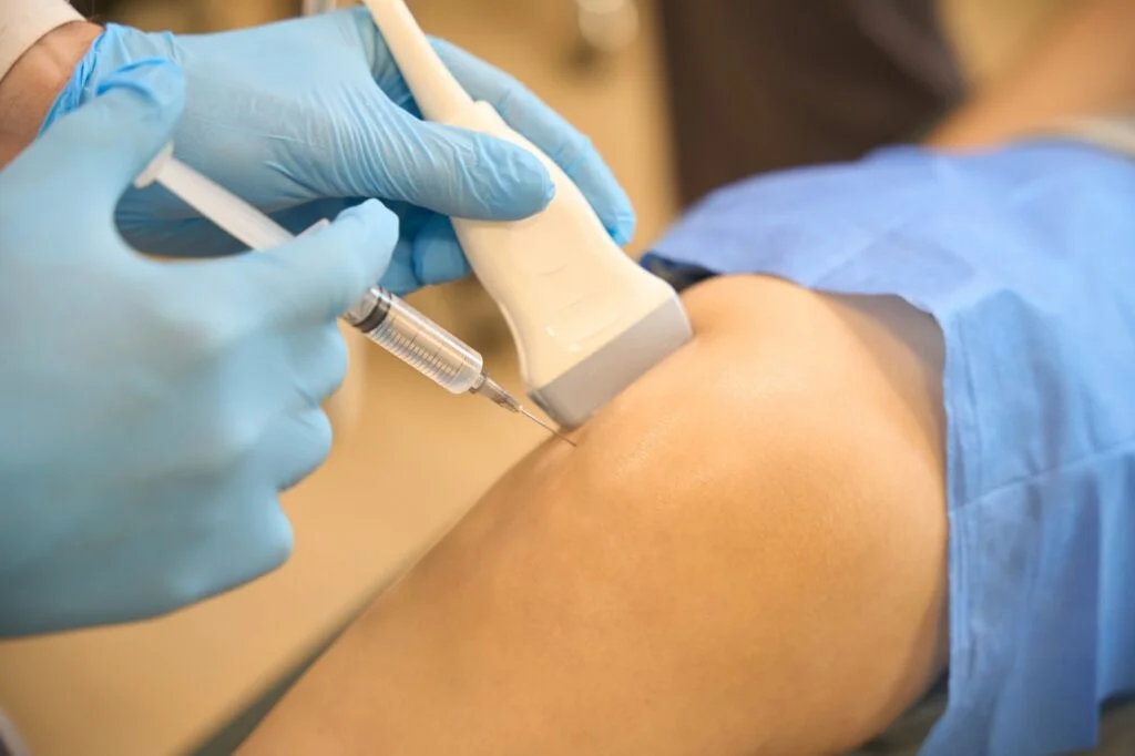 Doctor giving ultrasound-guided injection into knee
